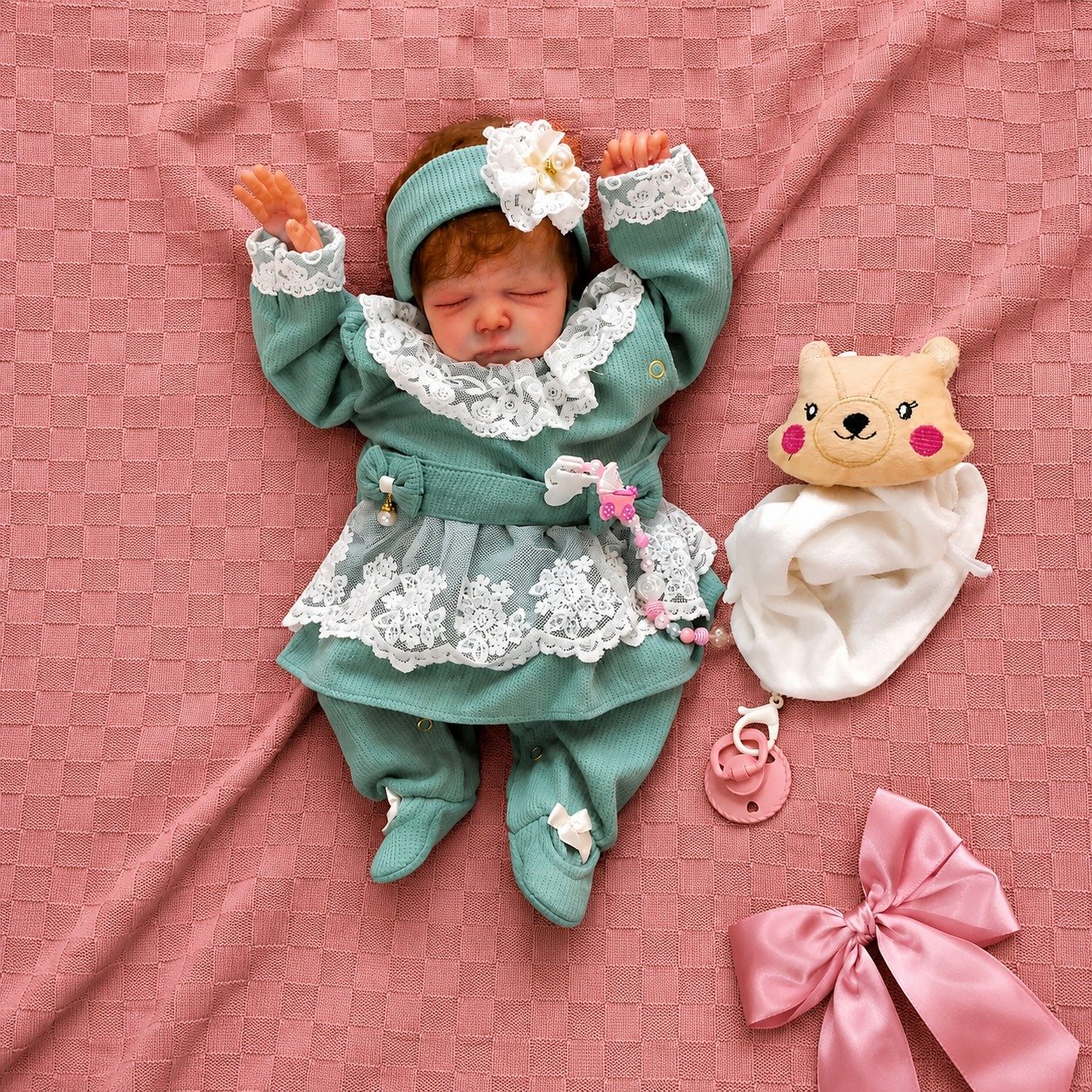 Bebê reborn menina Cayle com cabelinho fio a fio, deitada em saída de maternidade verde água com renda branca